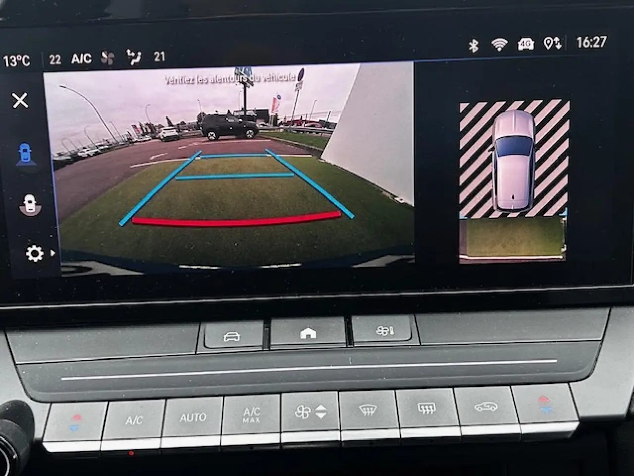 Écran multimédia montrant la caméra de recul de l'Opel Astra bleu clair, avec vue arrière et guidage de stationnement.