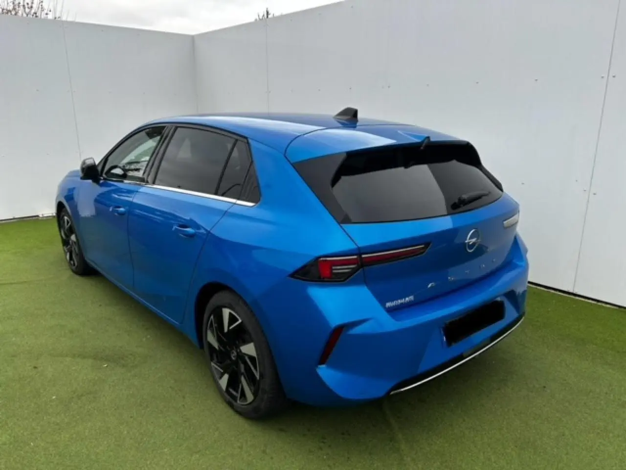 Opel Astra VI diesel bleu clair vue 3/4 arrière droit avec jantes alliage noir et vitres surteintées.