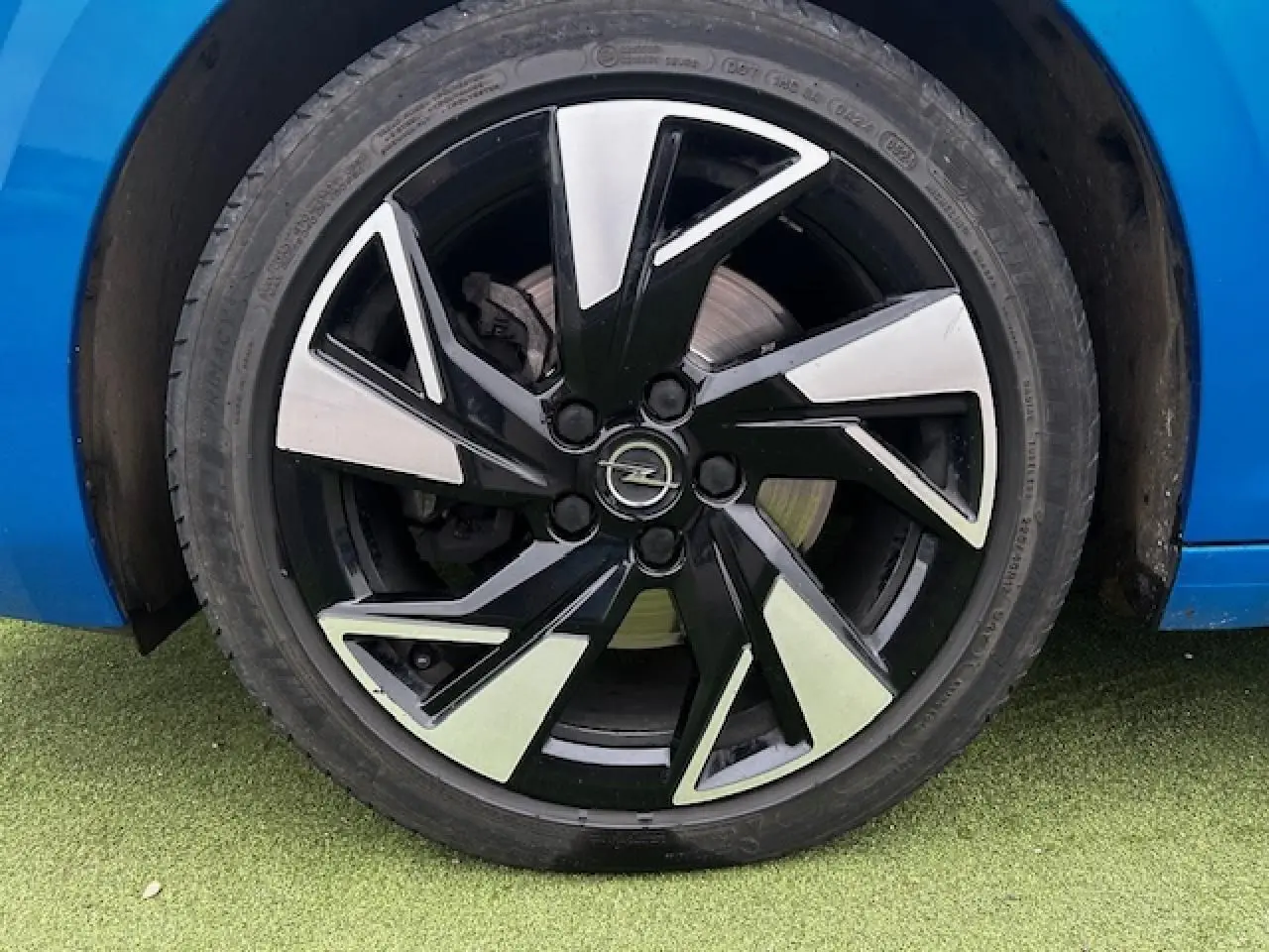 Gros plan sur la jante alliage 17 pouces noir et argent d'une Opel Astra bleu clair, côté arrière droit.