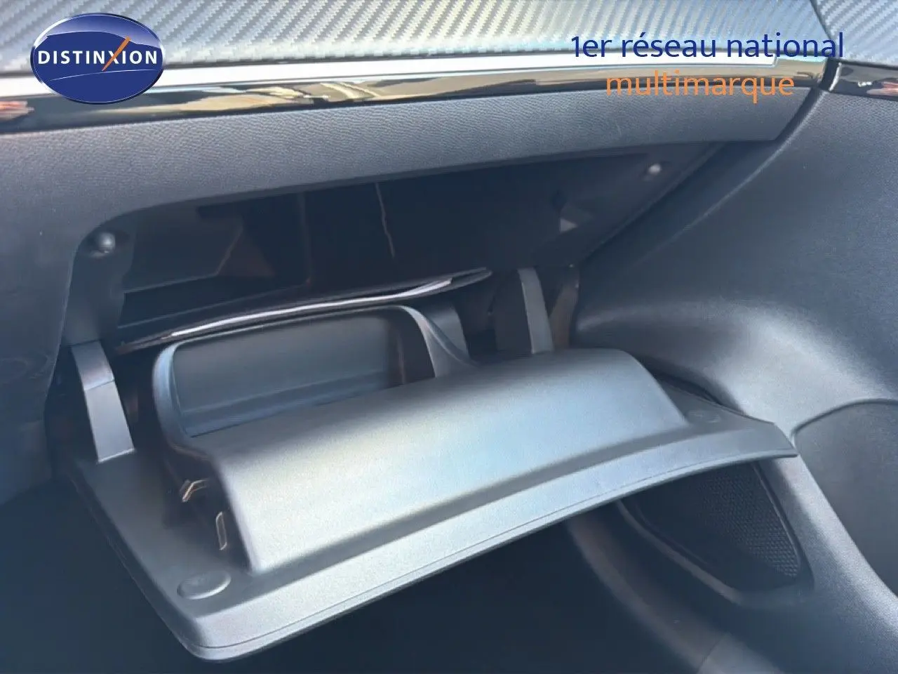 Gros plan sur la boîte à gants ouverte de la Peugeot 208 1.2 Hybrid 100ch Style, intérieur noir moderne.