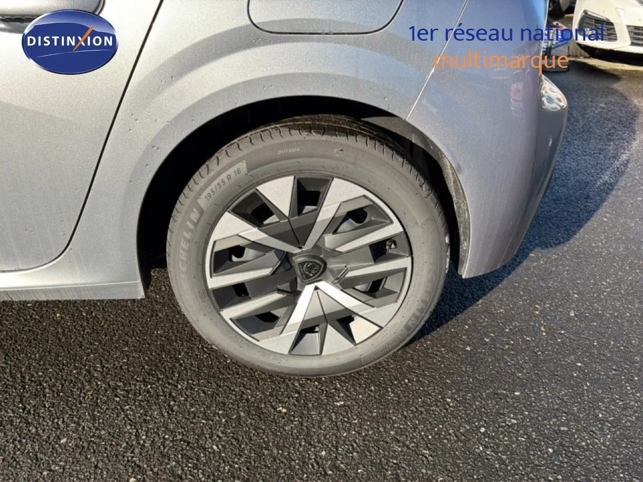 Gros plan sur la roue arrière gauche d'une Peugeot 208 gris Artense métal avec jante au design géométrique.