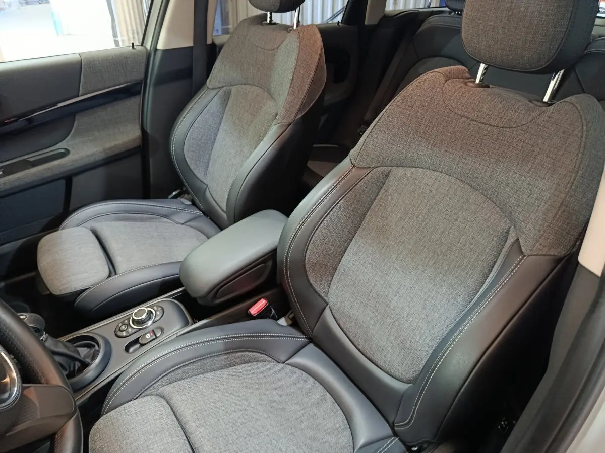 Vue rapprochée des sièges avant gris tissu et cuir du MINI COUNTRYMAN Cooper SE 2021, avec accoudoir central.