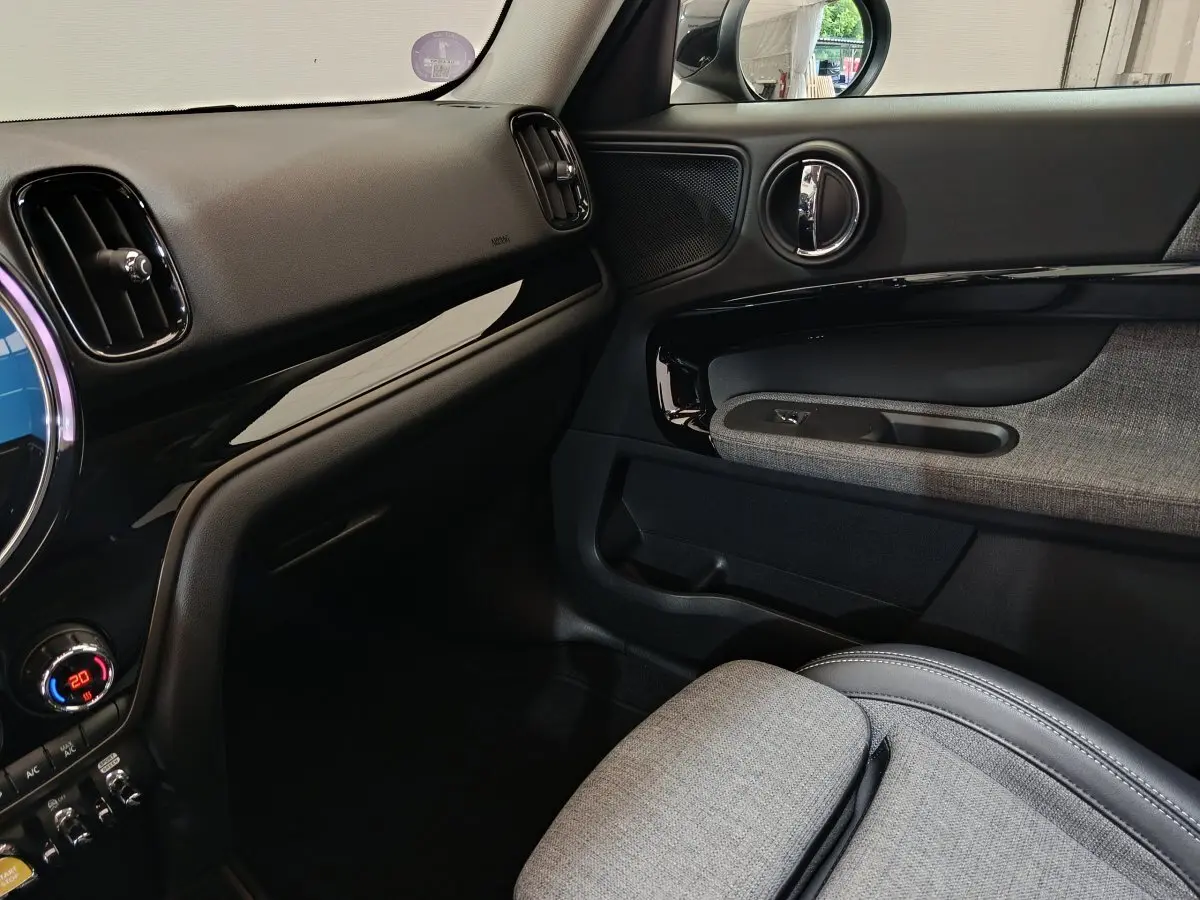 Vue intérieure côté passager du tableau de bord et porte avec garniture grise du MINI Countryman blanc 2021 Cooper SE.