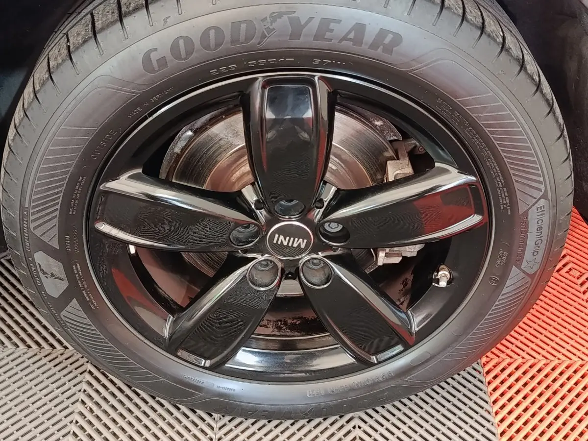 Gros plan sur la jante noire brillante de la MINI Countryman hybride, avec pneu Goodyear et logo MINI central.
