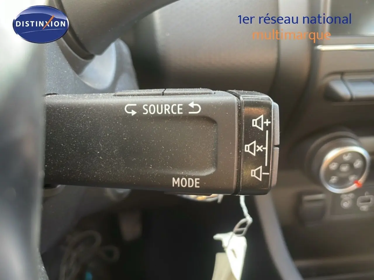 Gros plan sur la commande au volant de la Renault Clio blanche 2020, montrant les boutons source et mode audio.