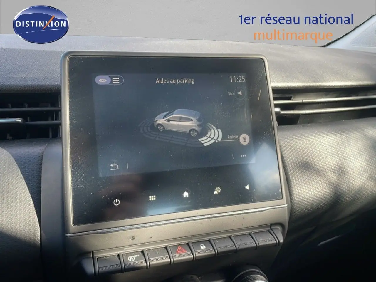 Écran tactile central montrant l'aide au parking dans l'habitacle d'une Renault Clio blanc glacier de 2020.