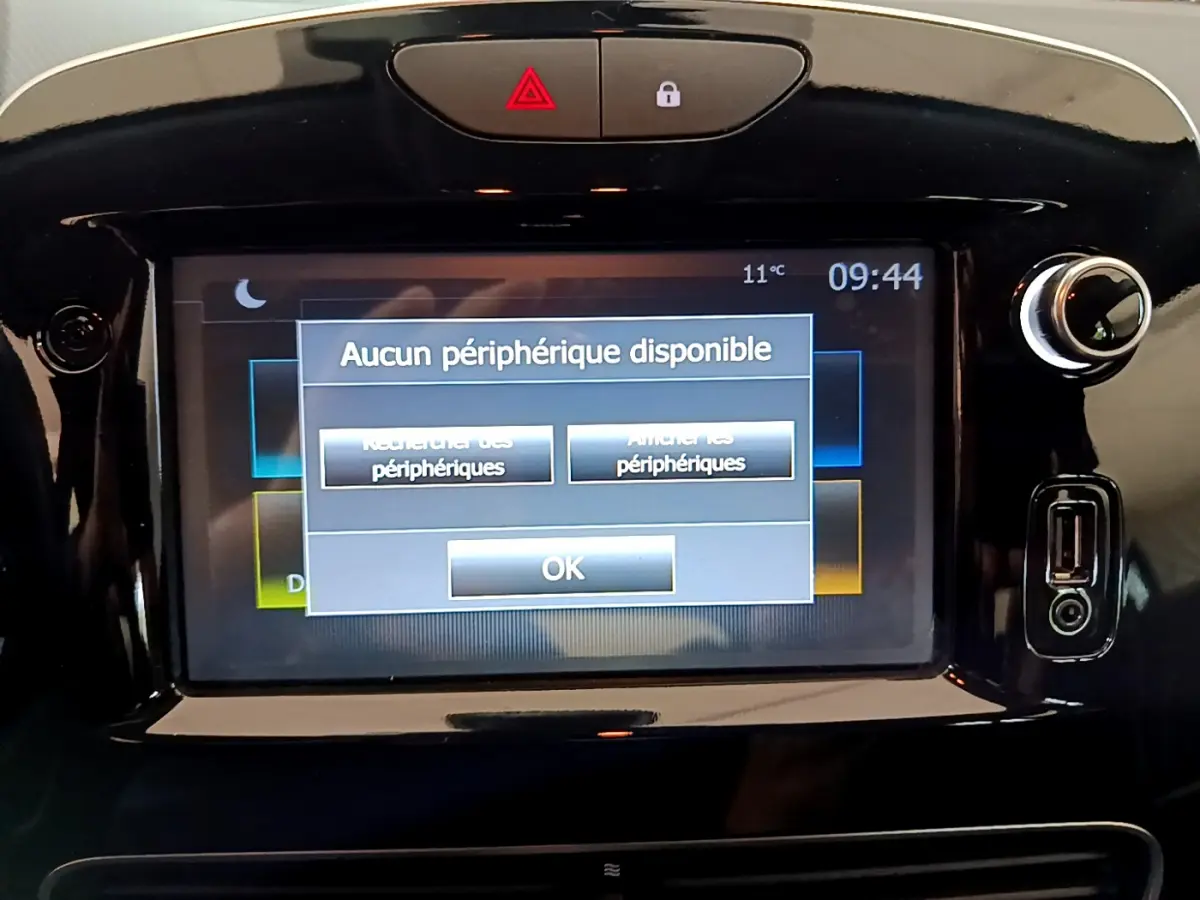 Écran tactile central affichant un message d'absence de périphérique dans une Renault Clio Business gris clair, vue frontale rapprochée.