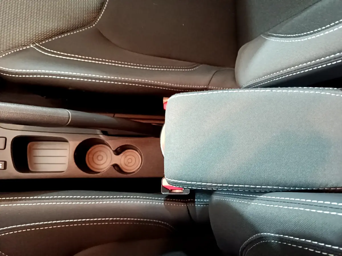 Vue plongeante sur la console centrale et accoudoir en tissu gris foncé avec surpiqûres blanches de la Renault Clio Business TCe 90.