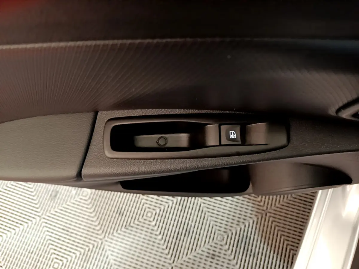 Gros plan sur la commande de lève-vitre côté conducteur de la Renault Clio Business gris clair, intérieur noir.