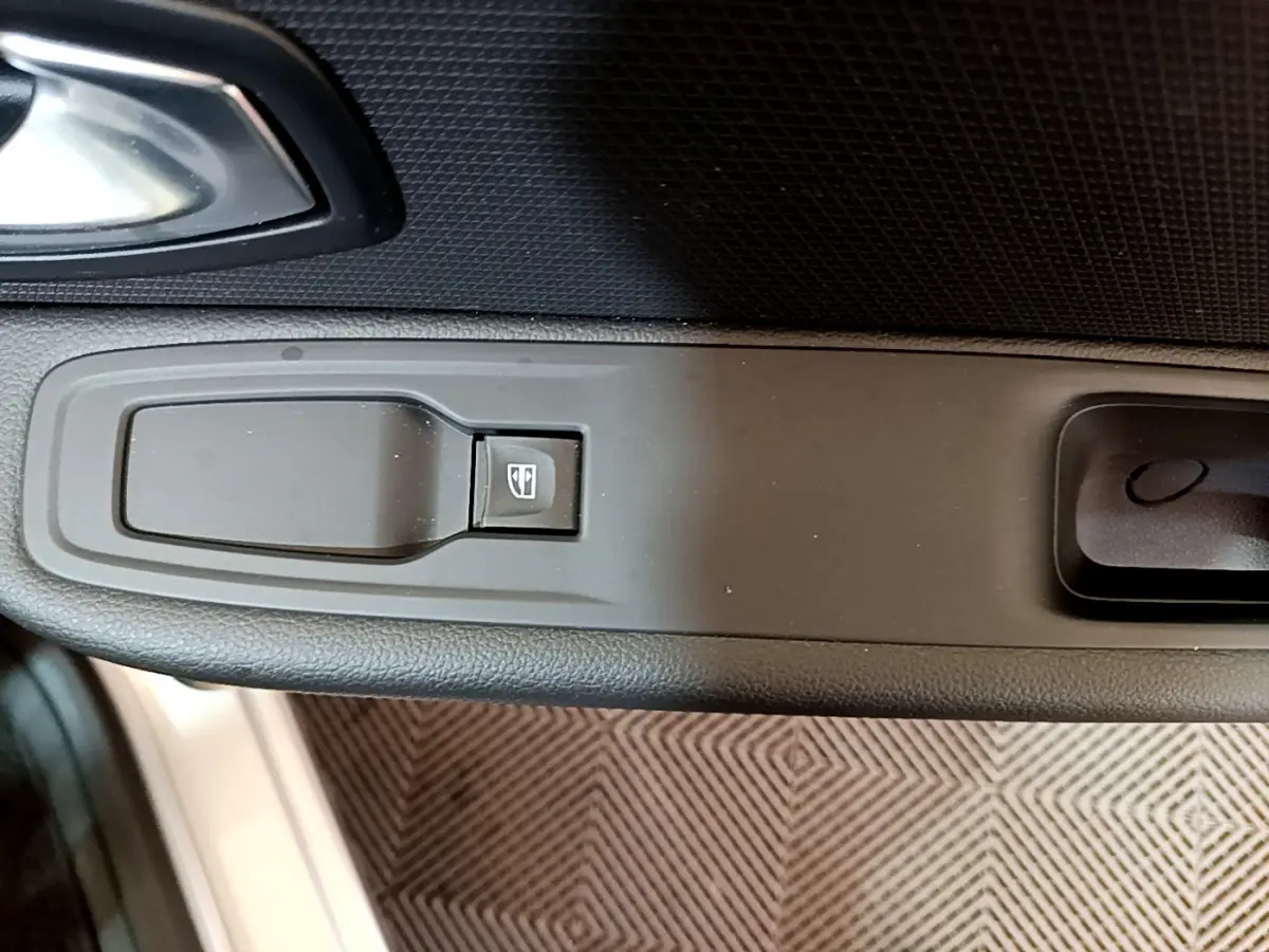 Gros plan sur le bouton de lève-vitre côté conducteur dans l'intérieur noir de la Renault Clio Business gris clair 2019.