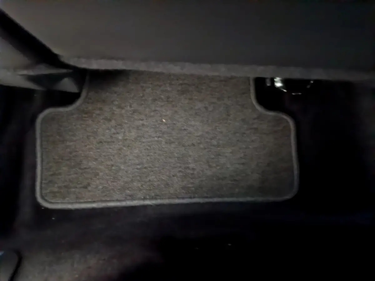 Tapis de sol gris foncé vu de près sous le tableau de bord côté conducteur d'une Renault Clio Business TCe 90 2019.