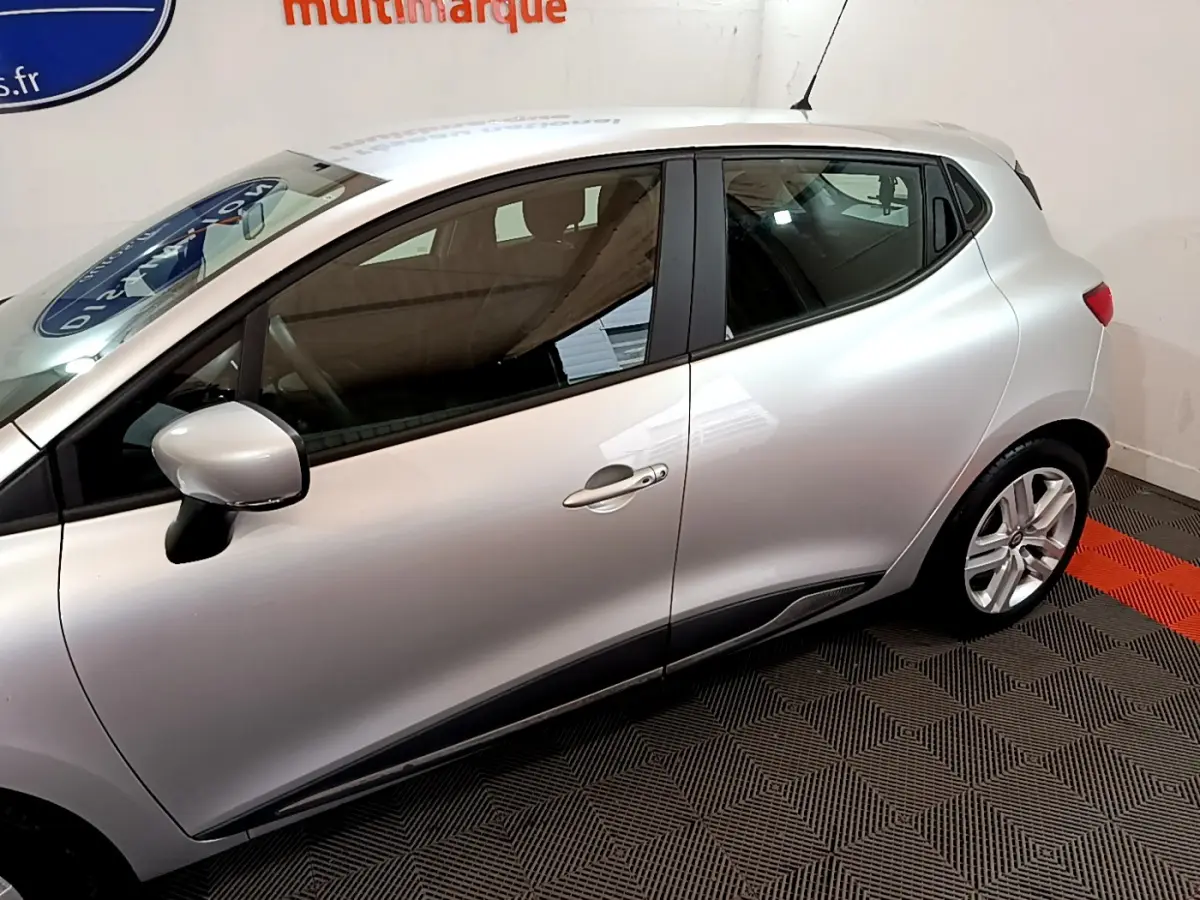 Profil côté gauche d'une Renault Clio Business TCe 90 gris clair, avec jantes alliage et poignées de porte assorties.