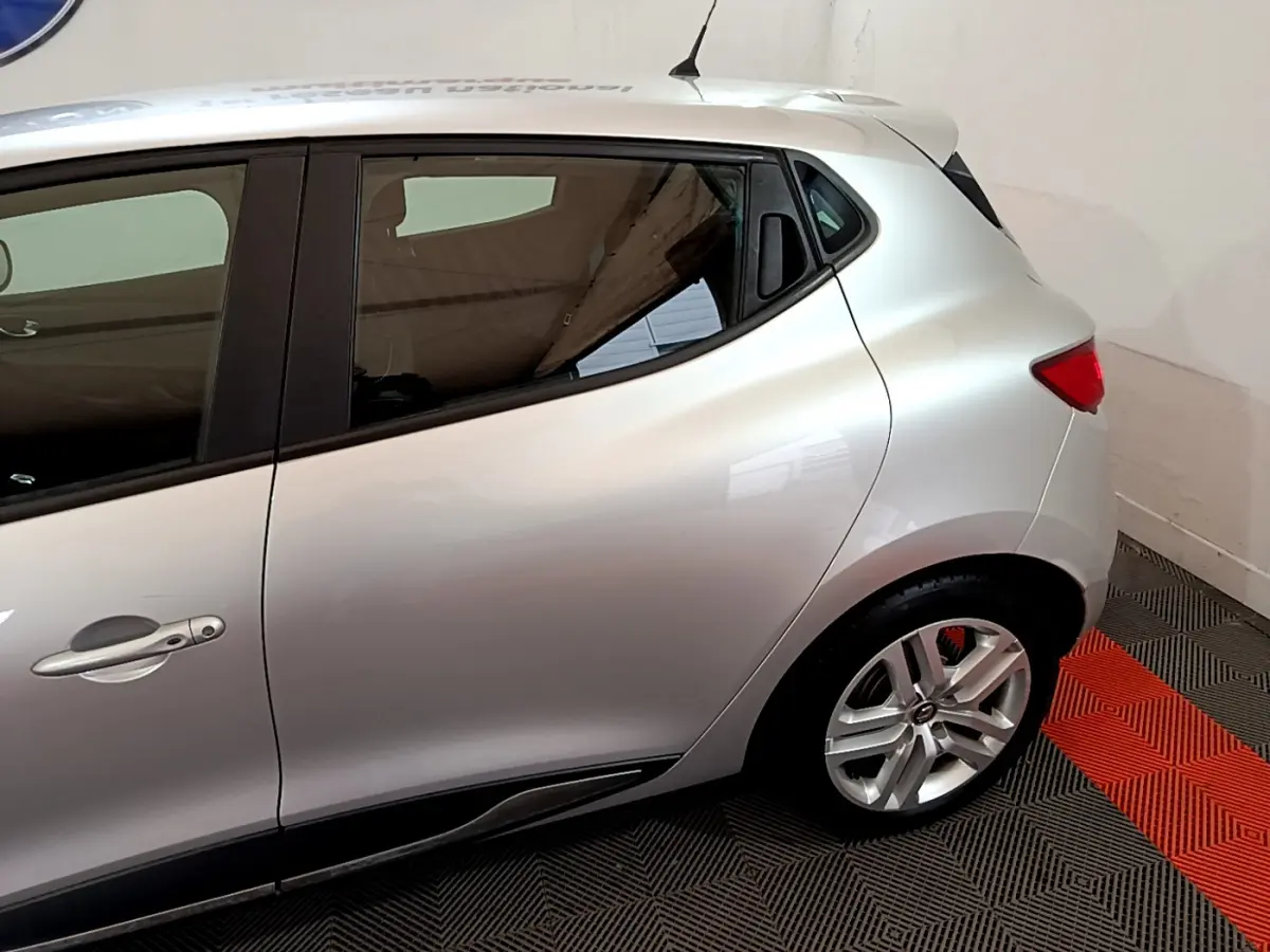 Vue latérale côté gauche d'une Renault Clio Business TCe 90 gris clair, mettant en valeur la porte arrière et la jante alliage.