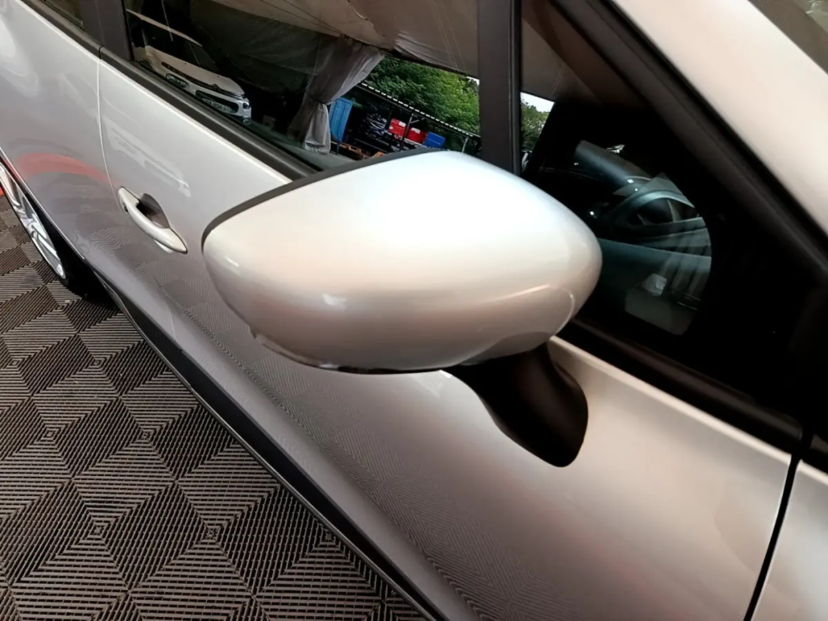 Gros plan sur le rétroviseur côté gauche d'une Renault Clio Business TCe 90 gris clair, avec reflet du véhicule.