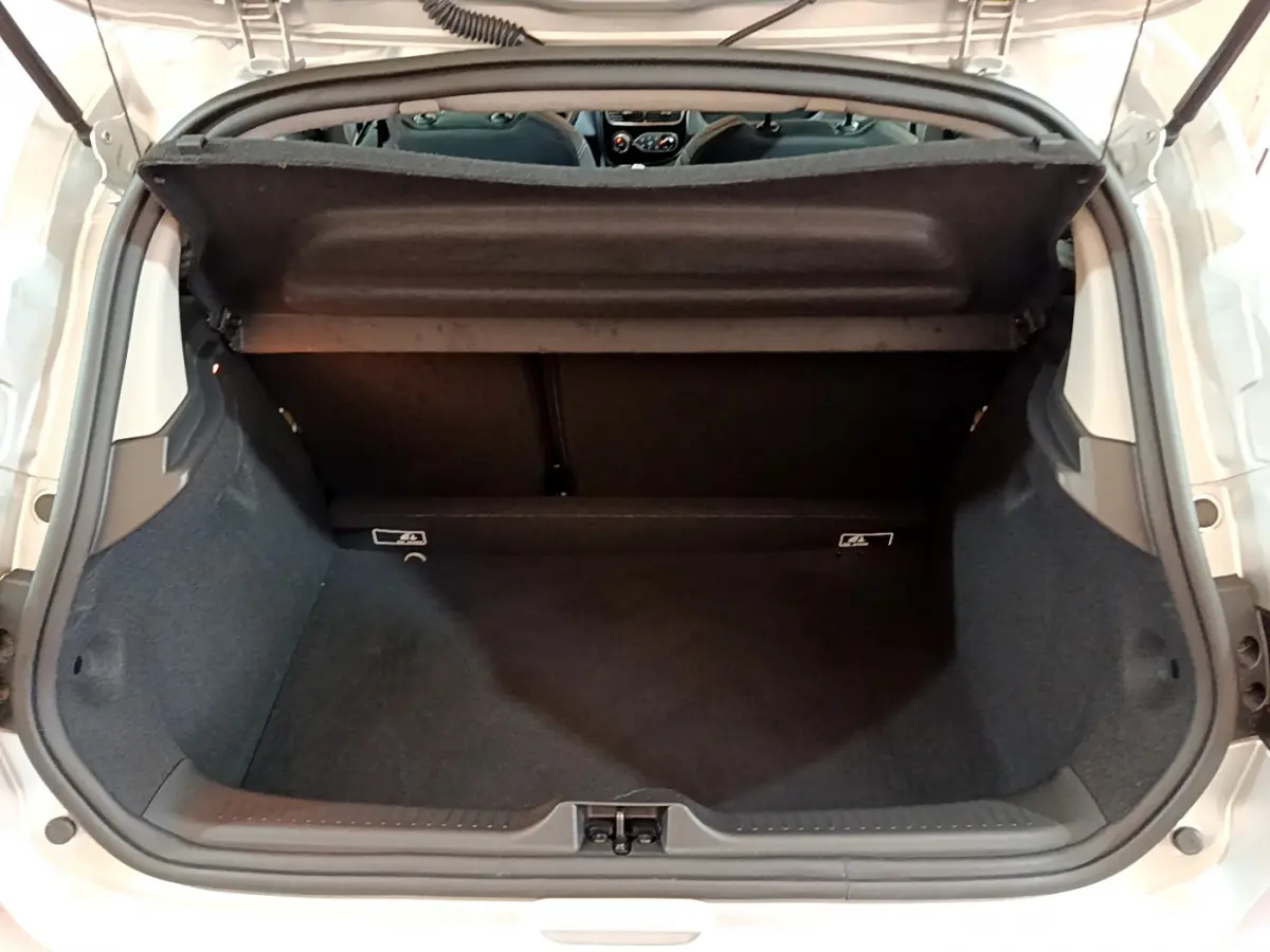 Vue plongeante sur le coffre ouvert d'une Renault Clio Business TCe 90 gris clair, intérieur spacieux et propre.