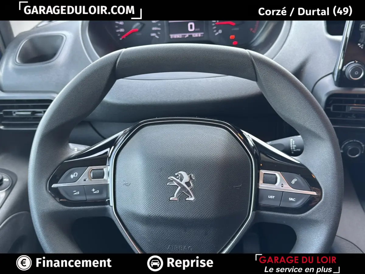 Vue rapprochée du volant Peugeot Rifter bleu 2024, avec commandes intégrées et tableau de bord numérique en arrière-plan.