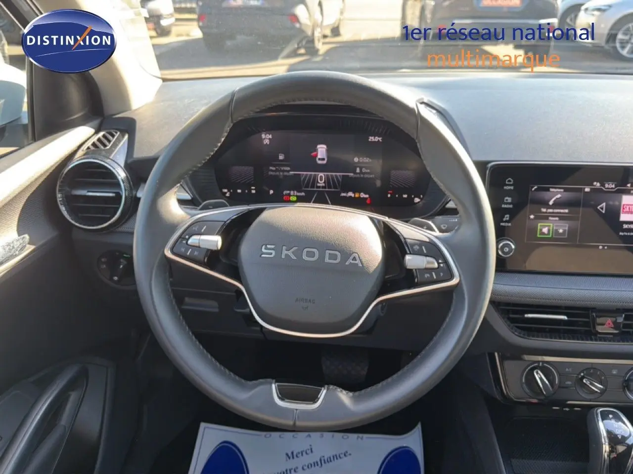 Vue intérieure centrée sur le volant SKODA noir et le tableau de bord digital lumineux d'une Fabia blanche Glacier 2025.