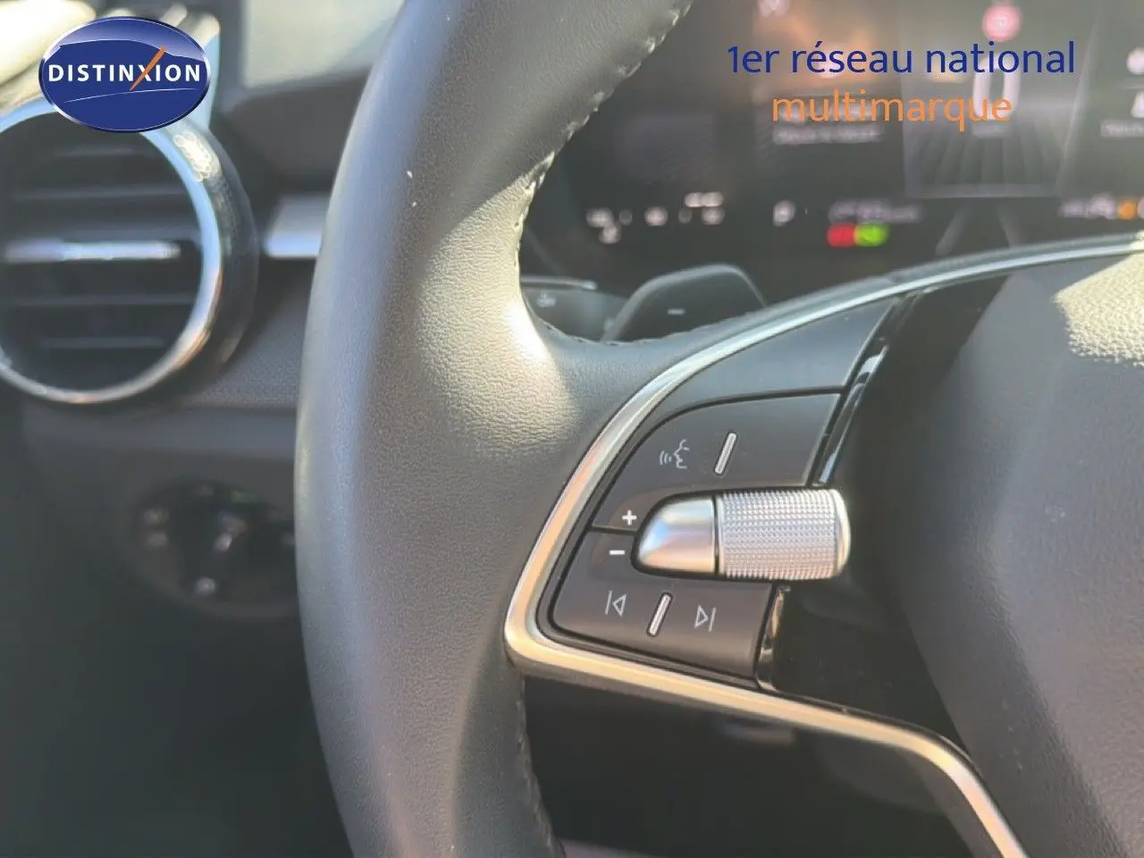 Gros plan sur les commandes multifonctions du volant noir de la Skoda Fabia 2025, avec aérateur circulaire en arrière-plan.