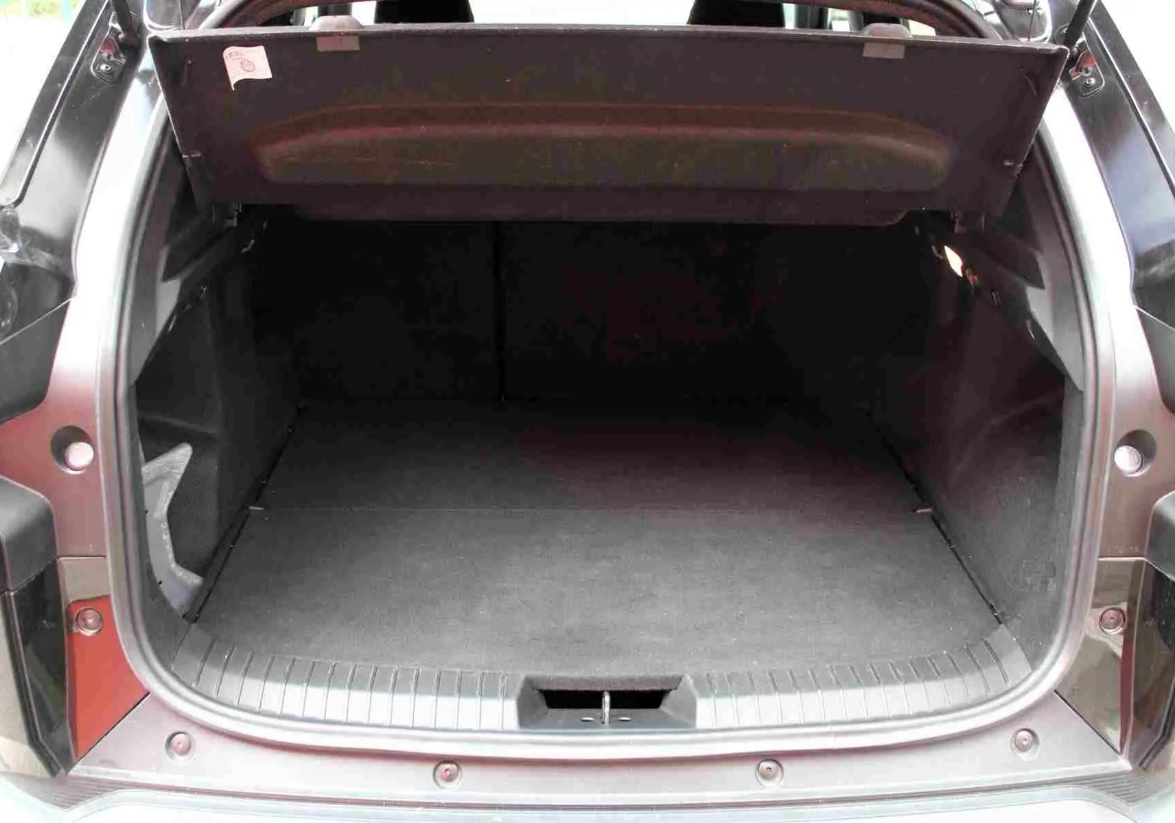 Coffre ouvert d'un Dacia Duster III noir, vue arrière centrée montrant l'espace de chargement vide.