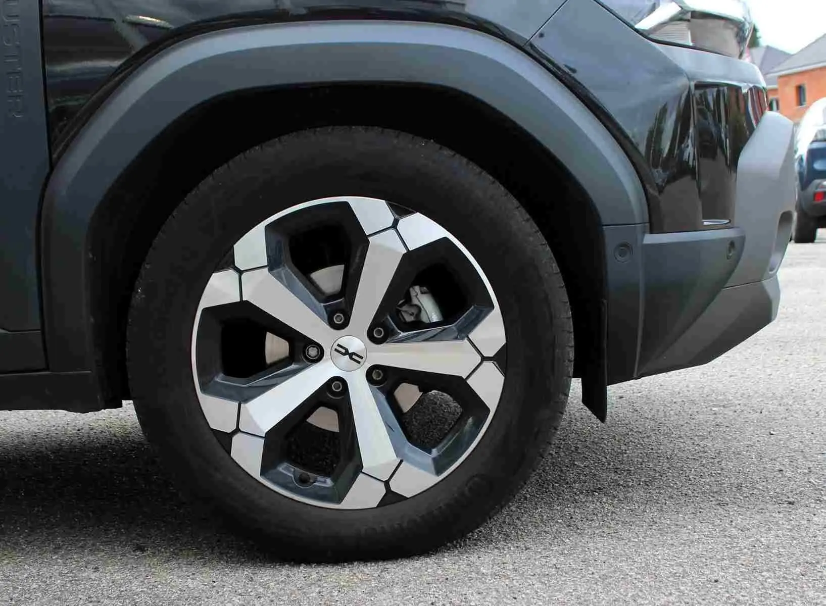 Gros plan sur la roue avant droite du Dacia Duster noir 2025 avec jante alliage diamantée Tagasan.