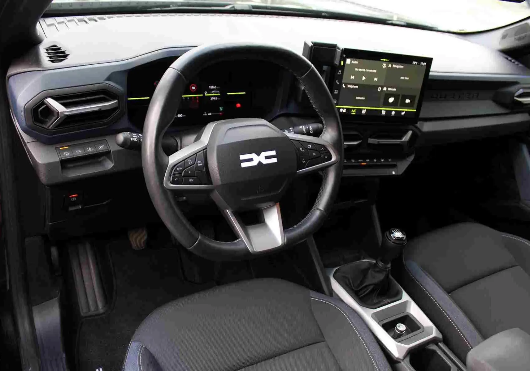 Intérieur du Dacia Duster III noir, vue du poste de conduite avec volant multifonction et écran tactile central.