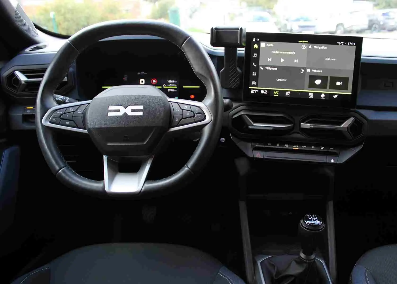 Vue intérieure centrée sur le volant et la console centrale du Dacia Duster 2025, avec écran tactile et levier de vitesses manuel.