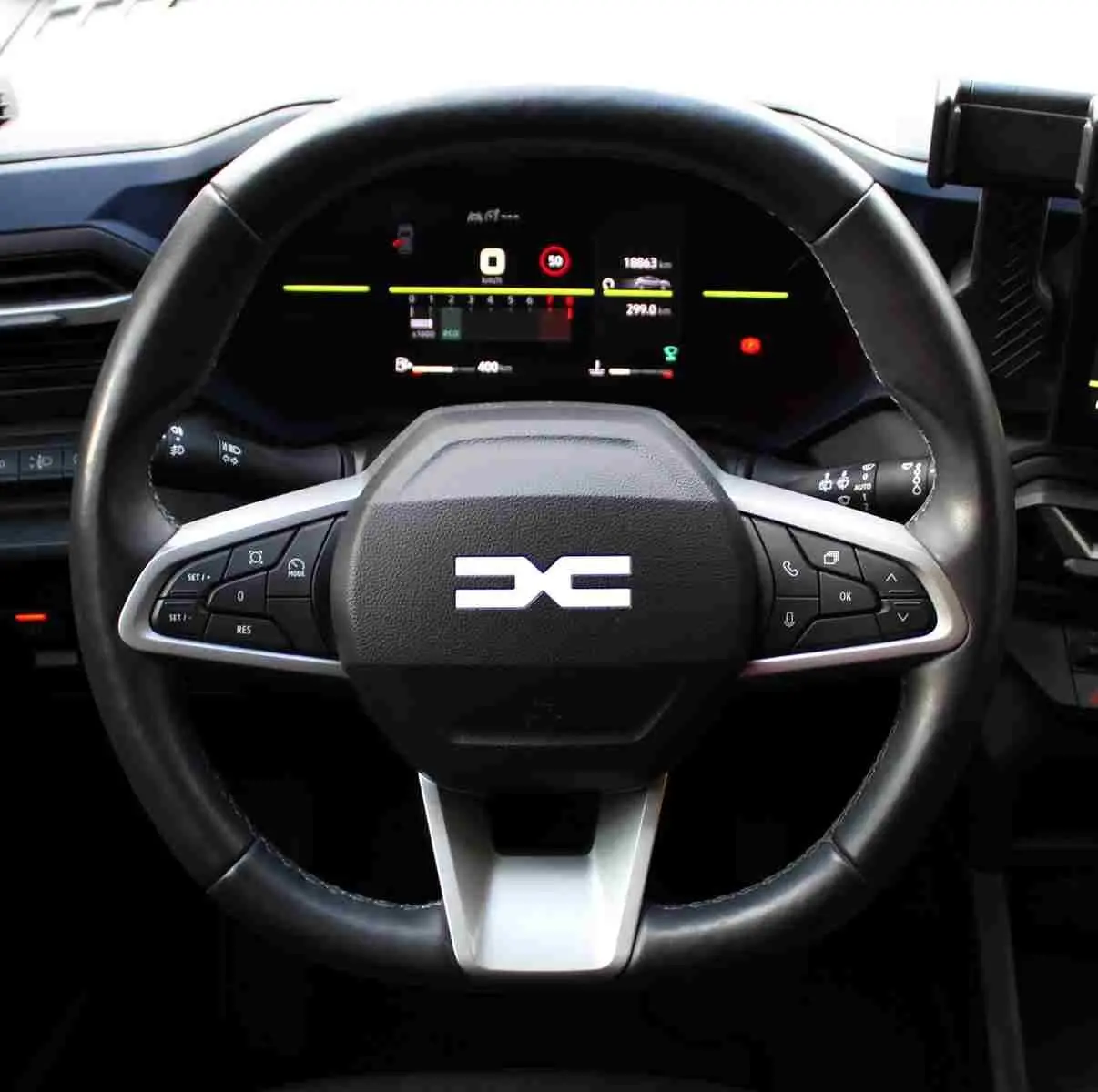 Vue rapprochée du volant noir de la Dacia Duster 2025 avec commandes intégrées et tableau de bord digital.