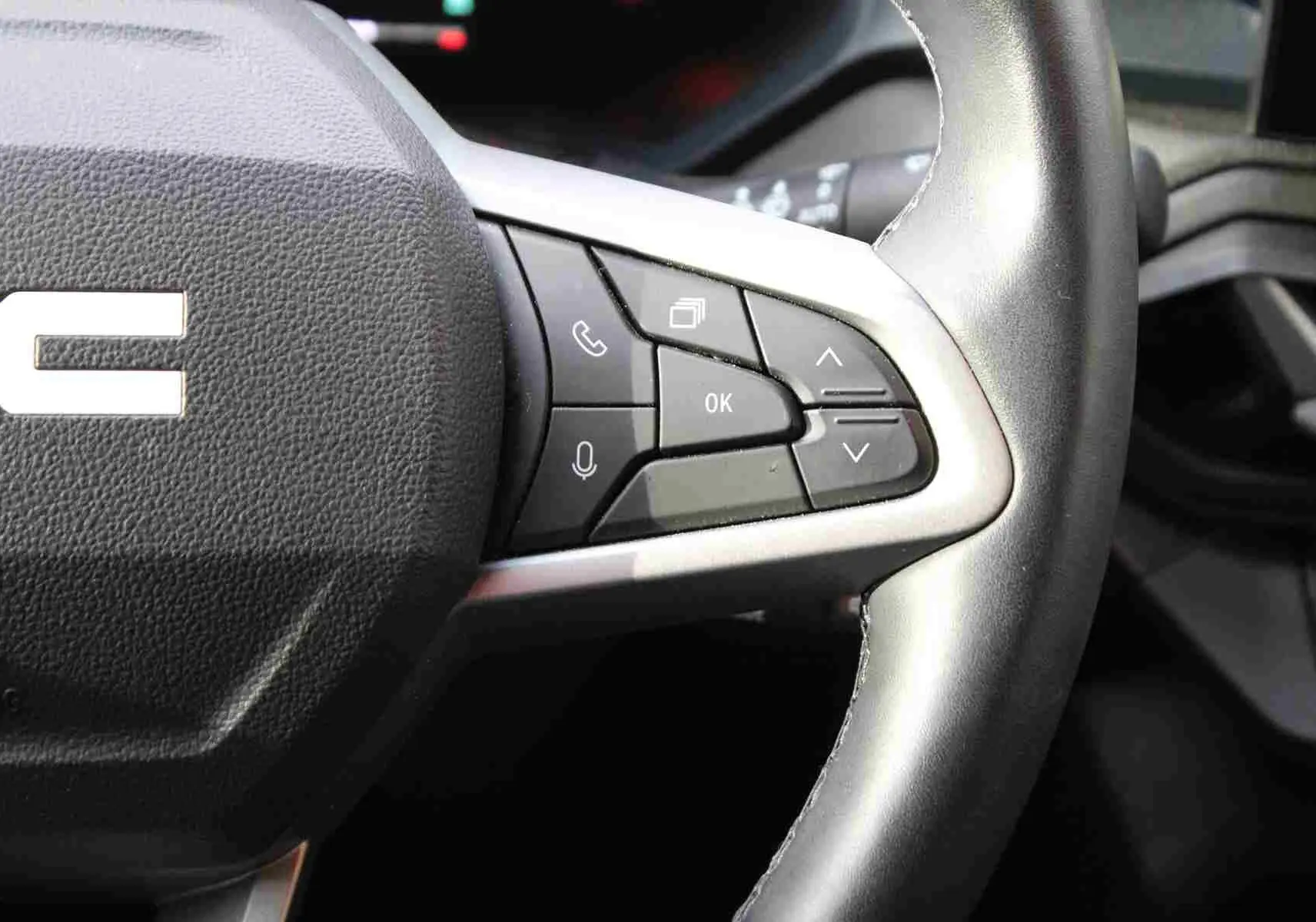 Gros plan sur le volant noir du Dacia Duster 2025 avec commandes multifonctions et finition argentée.