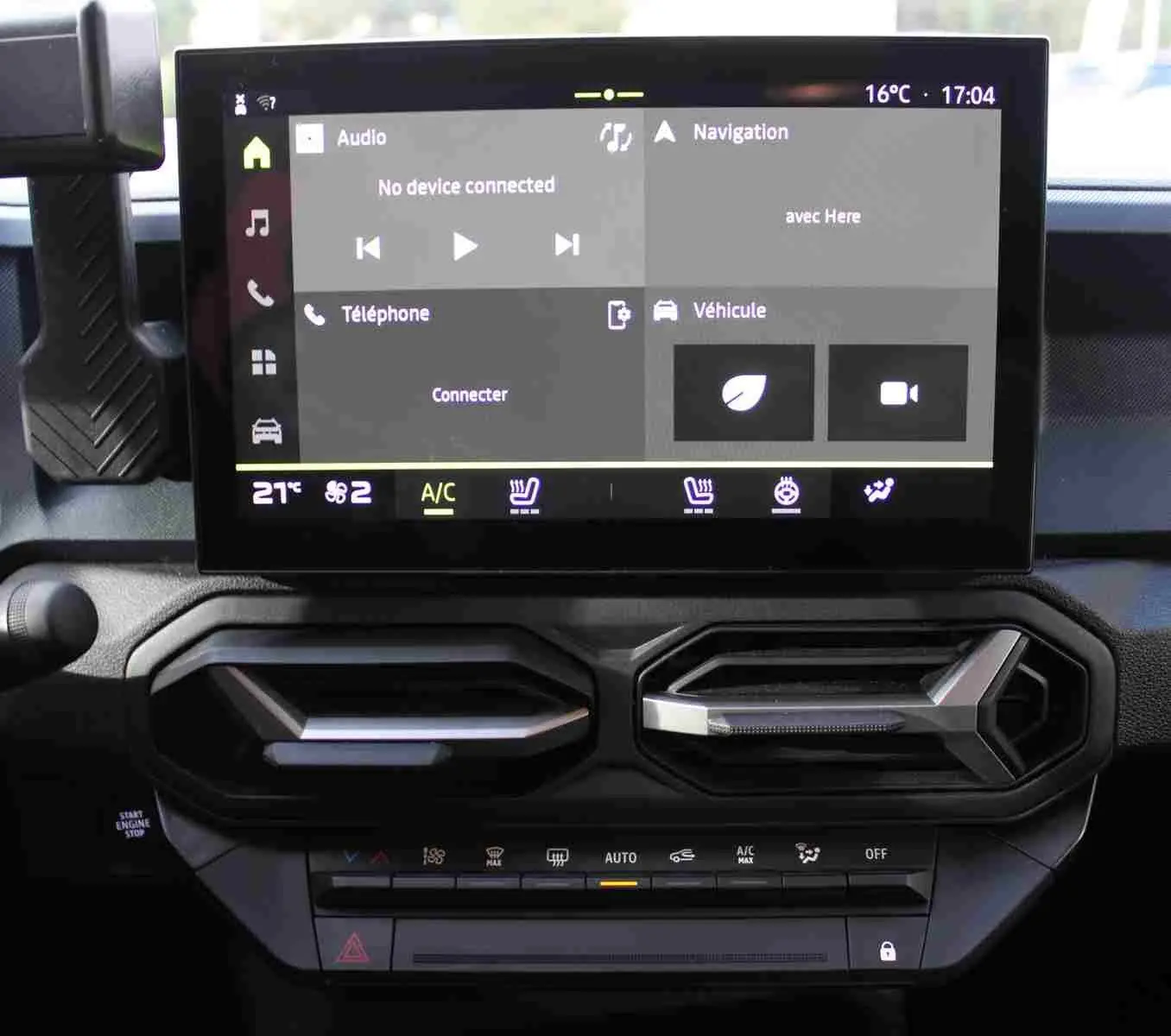 Écran tactile central avec interface CarPlay et aérateurs hexagonaux noirs du Dacia Duster noir, vue intérieure frontale.