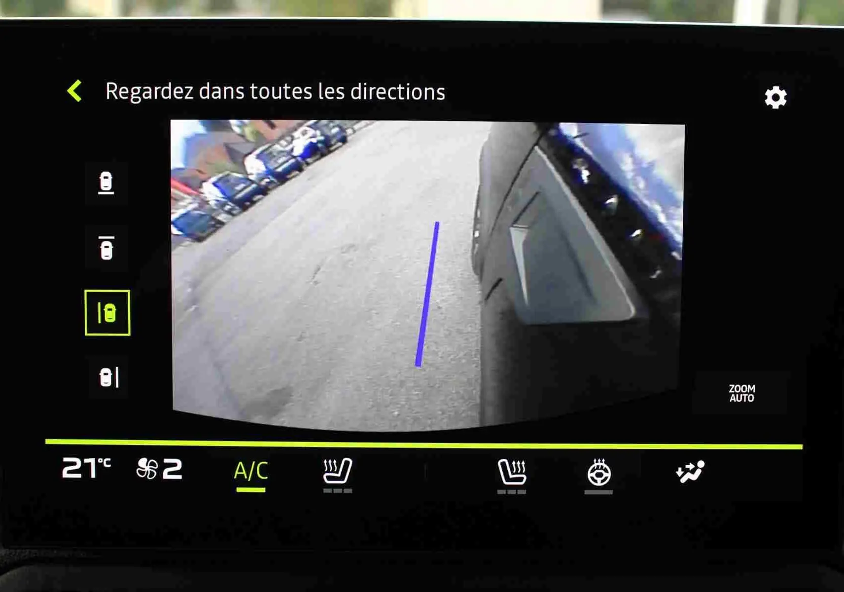 Vue écran caméra 360 du côté droit du Dacia Duster noir nacré, avec ligne guide bleue au sol visible.