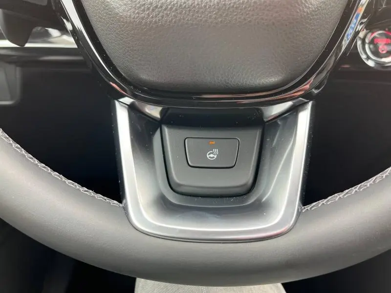 Gros plan sur le bouton de chauffage du volant en cuir noir du Honda CR-V blanc nacré 2024, finition Executive.