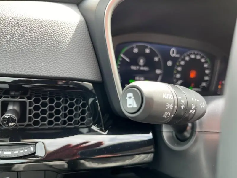 Gros plan sur la commande des phares et tableau de bord numérique du Honda CR-V blanc platine 2024.