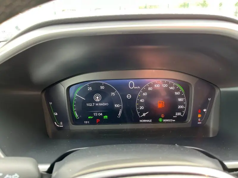 Tableau de bord numérique du Honda CR-V blanc platine 2024, affichant vitesse, radio et alertes au centre de l'instrumentation.