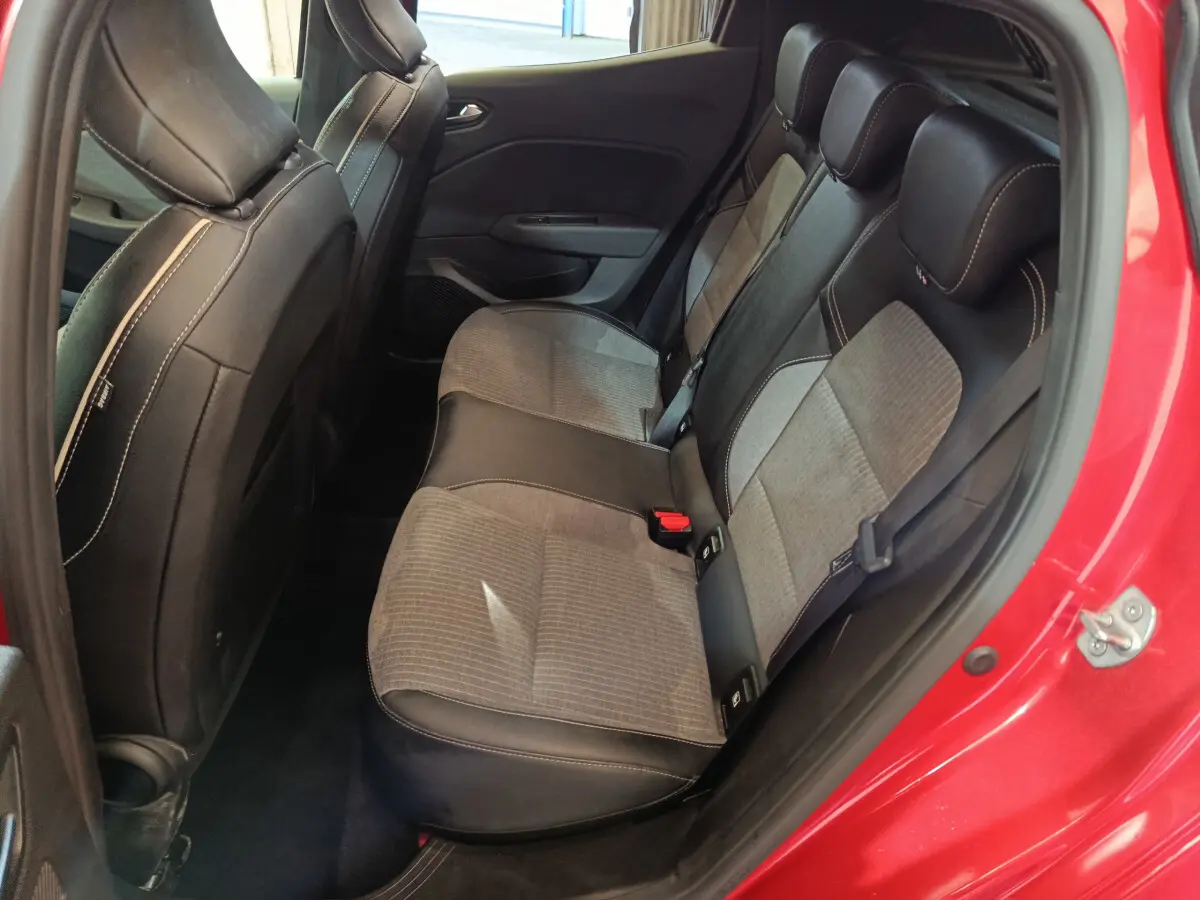 Vue côté gauche des sièges arrière bi-matière gris et noir d'une Renault Clio Techno rouge de 2024 avec porte ouverte.