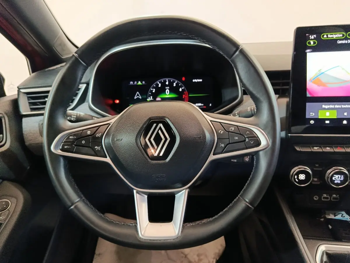 Vue rapprochée du volant cuir noir avec logo Renault et tableau de bord numérique de la Clio Techno 2024.