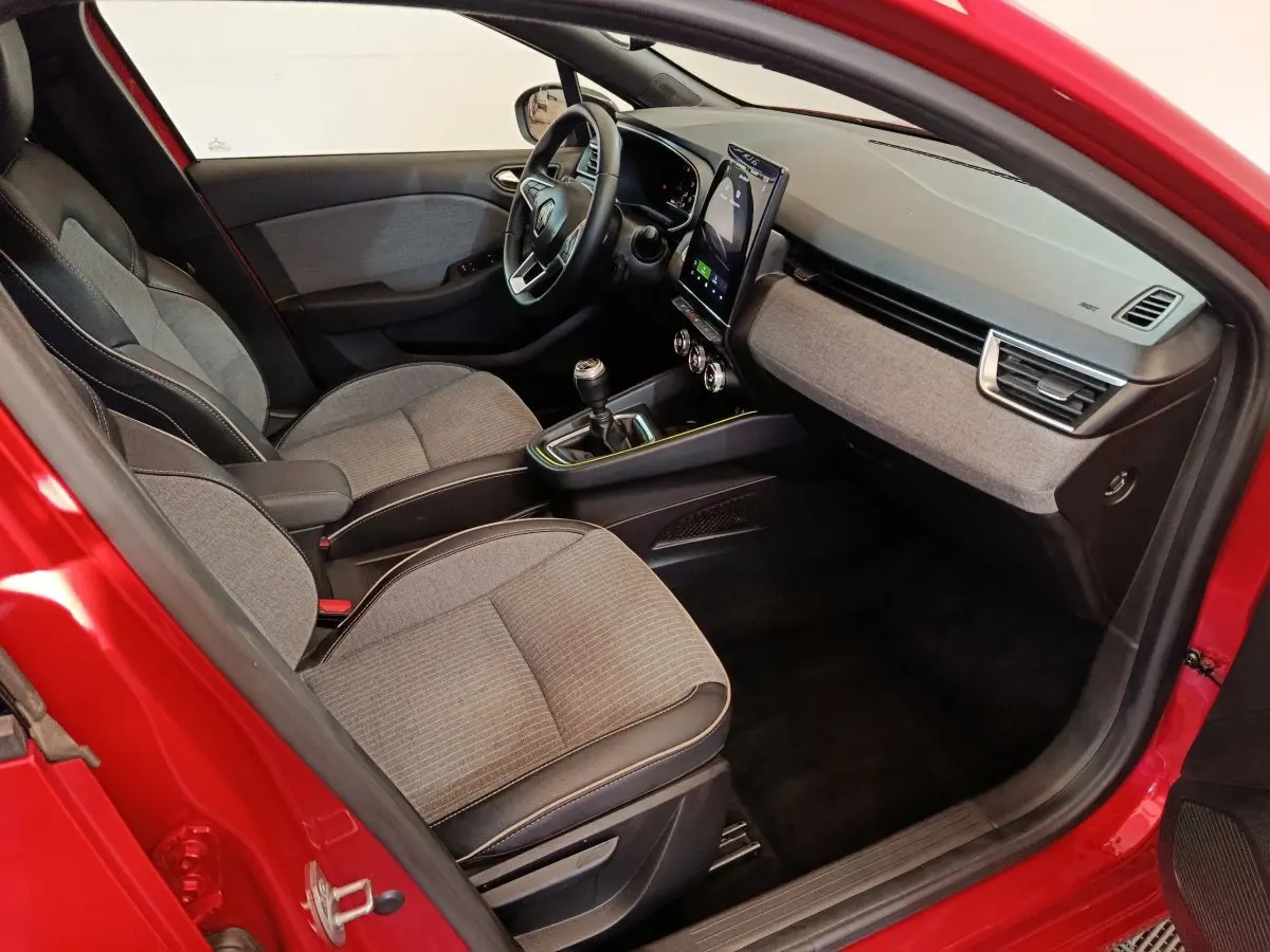 Intérieur de la Renault Clio Techno TCe 90 2024 rouge, vue côté conducteur, tableau de bord avec écran tactile vertical.