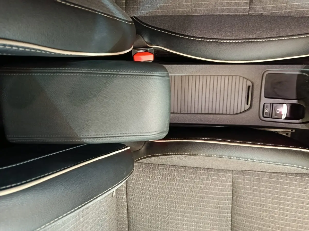 Vue plongeante sur la console centrale noire et les sièges gris foncé avec surpiqûres blanches de la Renault Clio 2024.