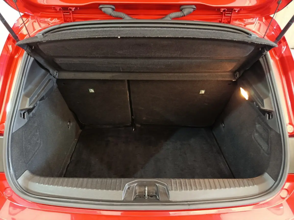 Coffre ouvert vu de l'arrière d'une Renault Clio Techno TCe 90 rouge, montrant un espace de chargement propre et éclairé.