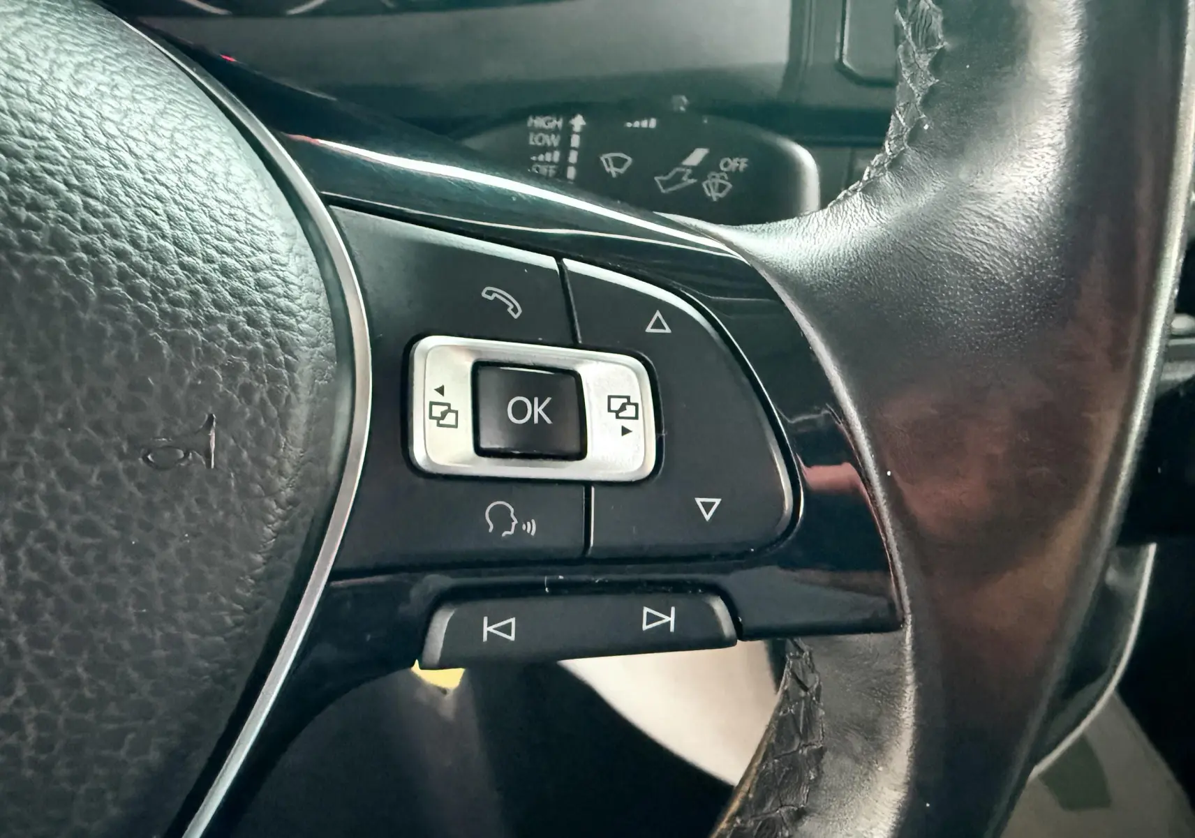 Gros plan sur les commandes multifonctions noires et argentées du volant en cuir du Volkswagen Transporter blanc L1H1 2018.