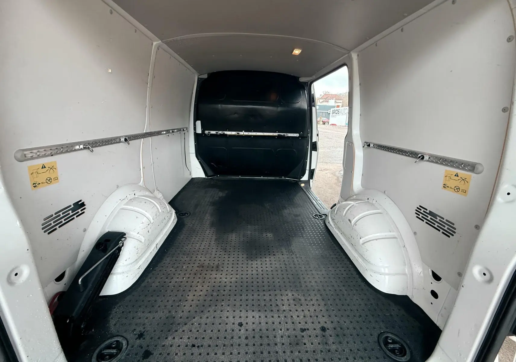 Vue intérieure arrière du Volkswagen Transporter L1H1 blanc de 2018, montrant l’espace de chargement vide avec sol noir antidérapant.