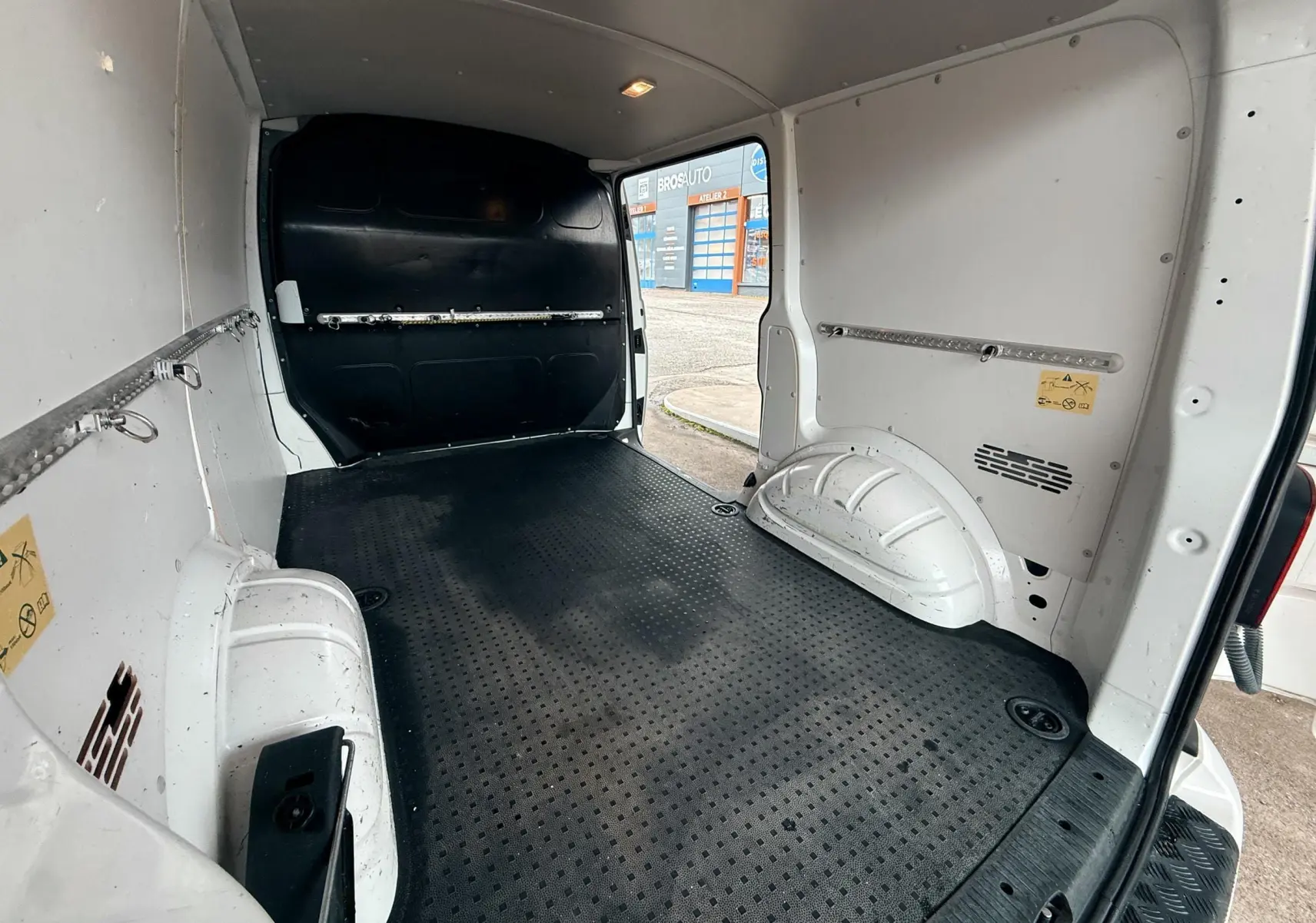 Vue intérieure arrière du Volkswagen Transporter blanc L1H1 2018, montrant l’espace de chargement avec sol antidérapant noir.