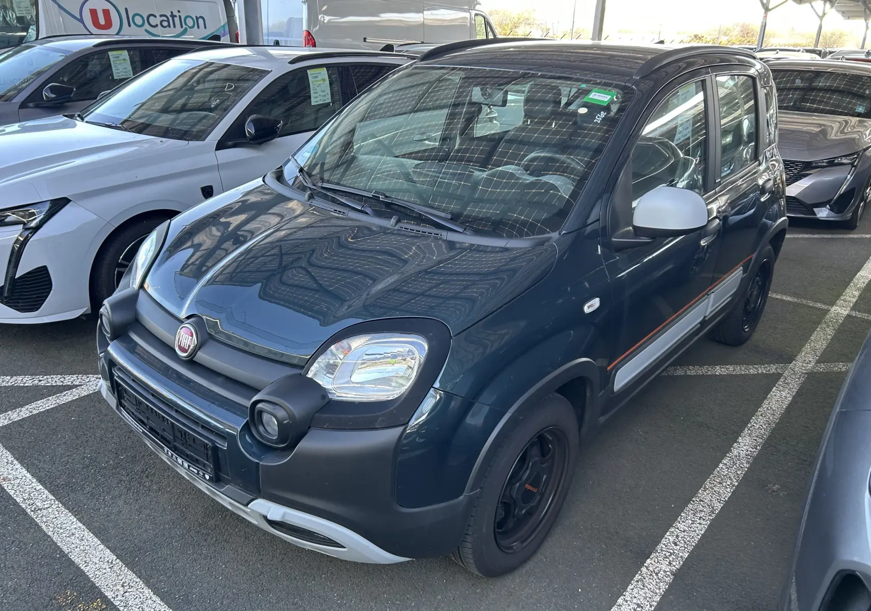 Vue 3/4 avant droite de la Fiat Panda City Cross gris minuit avec protections noires et calandre grise claire.