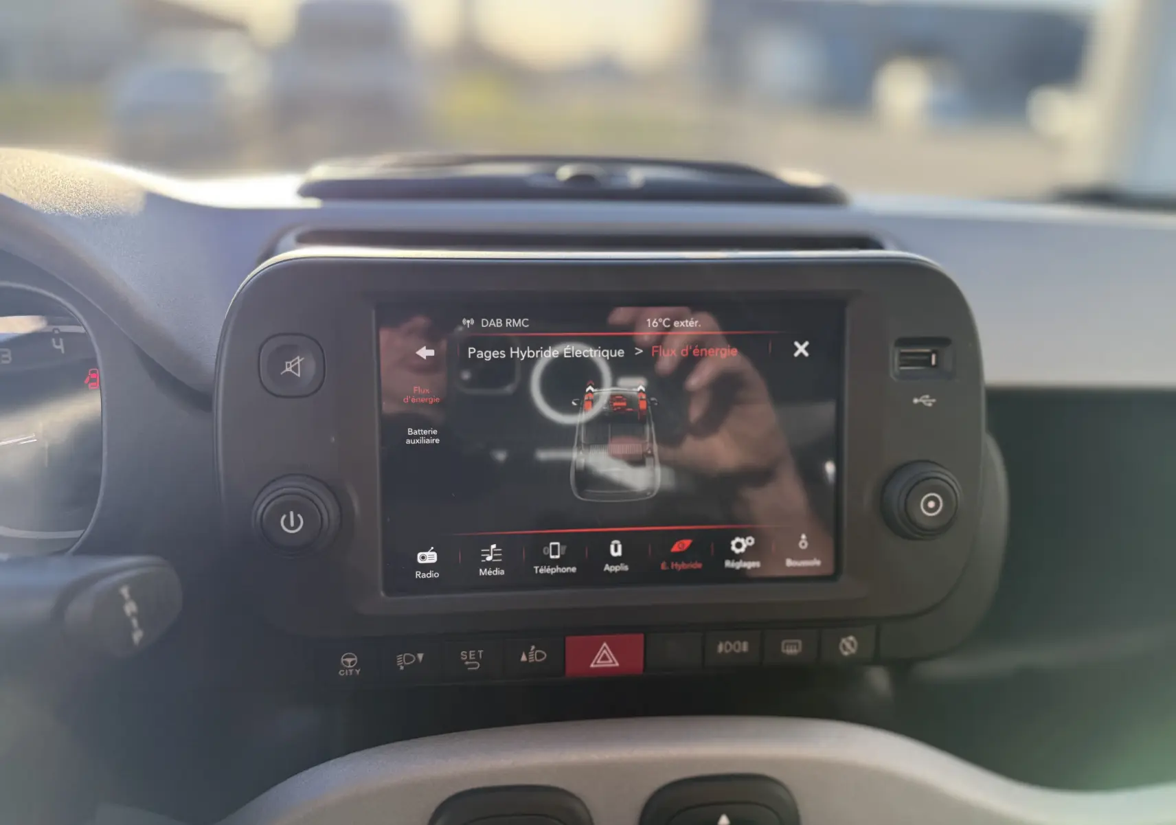 Vue rapprochée de l'écran tactile central de la Fiat Panda City Cross gris minuit, affichant le flux d'énergie hybride.