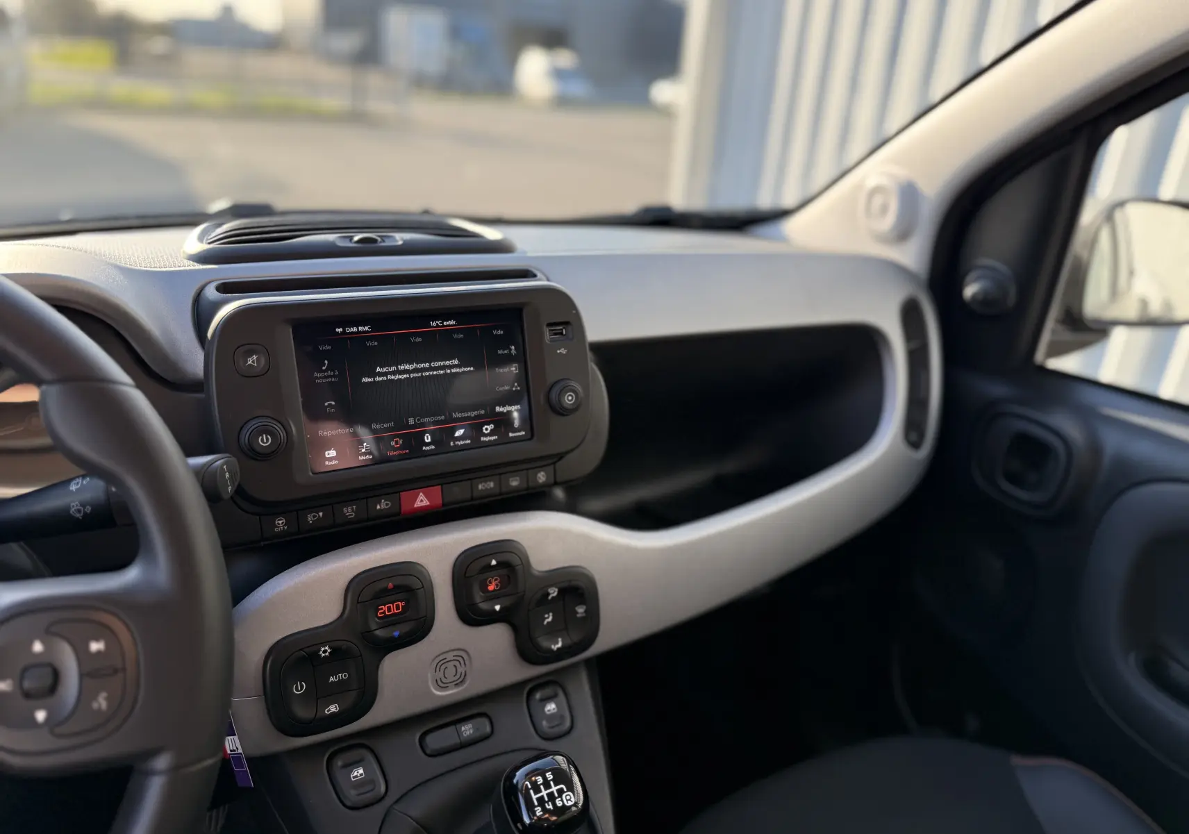 Vue intérieure côté conducteur de la FIAT Panda City Cross 2023, montrant le tableau de bord et la boîte manuelle.