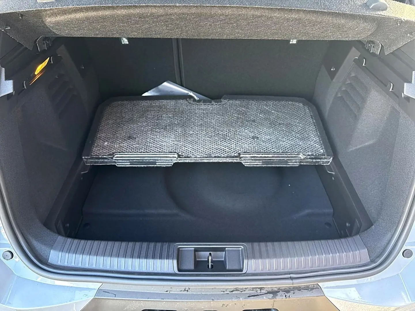 Coffre ouvert vu de l'arrière d'une Renault Symbioz gris cassiope avec plancher de coffre mobile et compartiment de rangement.