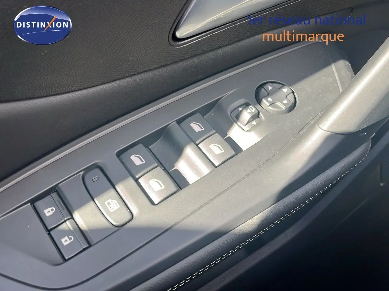 Gros plan sur les commandes des vitres et rétroviseurs côté conducteur d'une Peugeot 308 vert olivine métal.