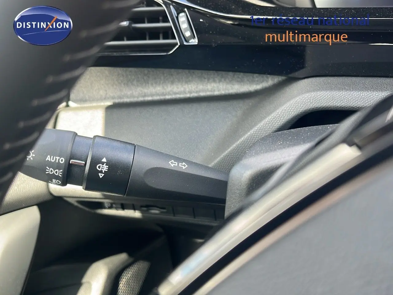 Détail de la commande des clignotants et feux sur le côté gauche du volant d'une Peugeot 308 vert olivine hybride 2024