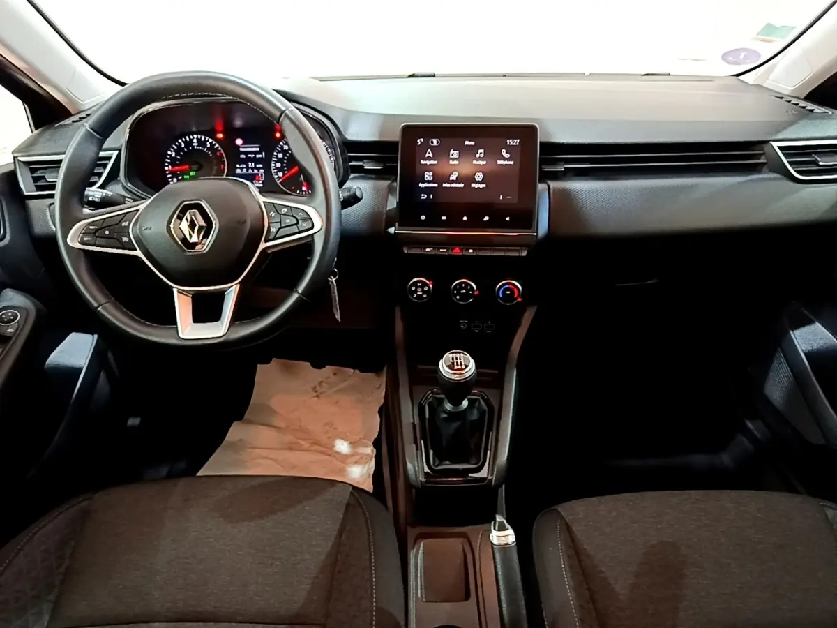 Vue intérieure frontale du tableau de bord noir de la Renault Clio Business TCe 90 avec volant cuir et écran tactile central.