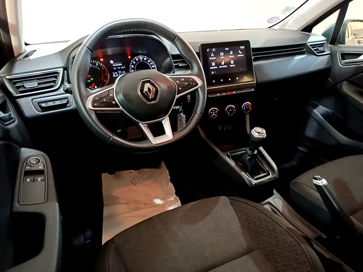 Vue intérieure avant de la Renault Clio Business TCe 90 2022, volant cuir, écran tactile central et levier de vitesse manuel visibles.