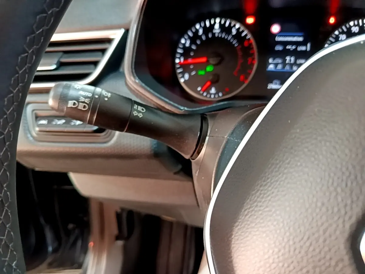 Gros plan sur le commodo gauche et le tableau de bord éclairé d'une Renault Clio Business TCe 90 gris foncé, 2022.